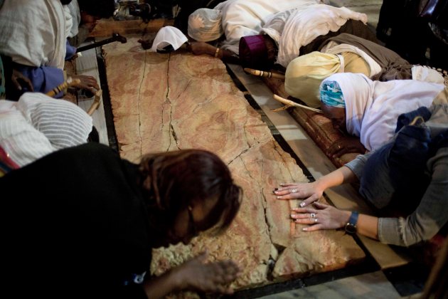 Fieles oran en la Piedra de la Unión, donde según la creencia, Jesús fue colocado después de que lo crucificaran, en el interior de la Iglesia del Santo Sepulcro en Jerusalén, el jueves 17 de abril de 2014. (AP Foto/Ariel Schalit)