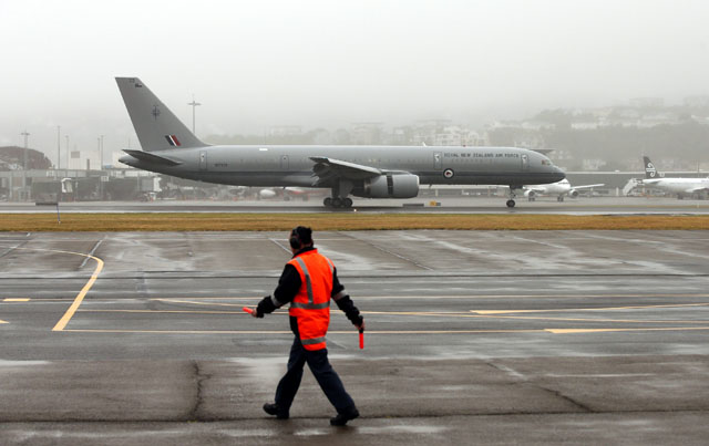 A member of the ground staff watches the plane carrying Prince William, his wife and their son Prince George as it arrives at Wellington airport