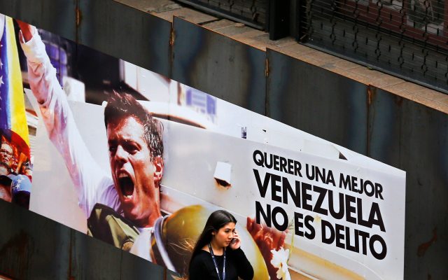 A woman walks past a banner with a picture of jailed opposition leader Leopoldo Lopez in Caracas