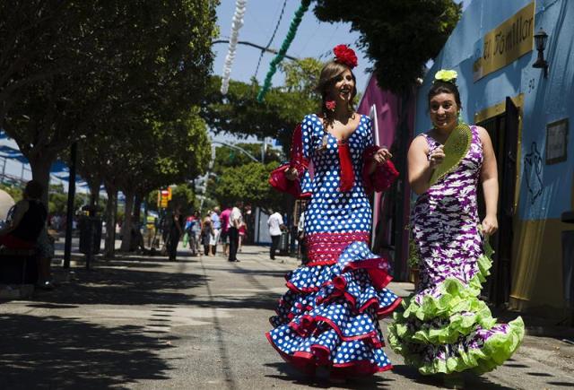 Jóvenes vestidas de flamenca pasean hoy por el Real de la Feria de Málaga 2014, que se inició el pasado 16 de agosto y finaliza el próximo día 23. EFE/Jorge Zapata