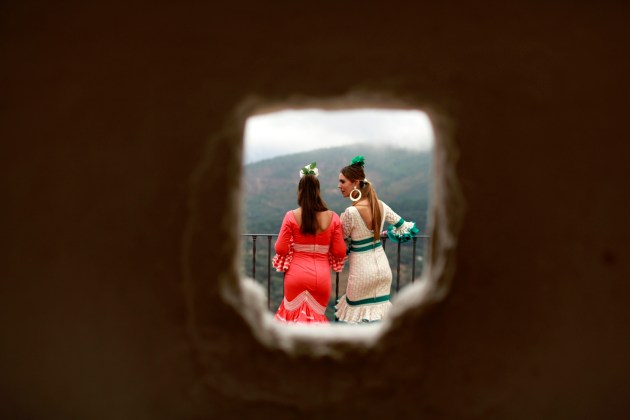Pilgrims wearing flamenco outfits are pictured through a window during a pilgrimage in Alajar, southwest Spain