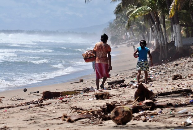 A woman and a girl walk along the beach covered in debris after Hurrican Odile hit the area, in Acapulco