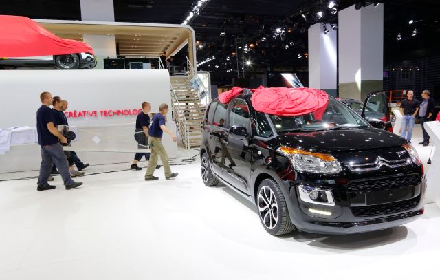 Employees prepare a Citroen C4 car which is displayed at French carmaker Citroen showcase for the Paris Mondial de l'Automobile