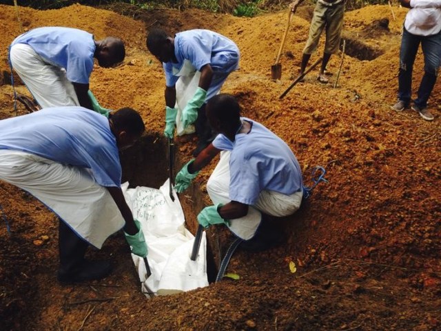 Foto; Un grupo de voluntarios desciende un cuerpo, preparado con medidas funerarias seguras, a una tumba en Kailahun, Sierra Leona / Reuters