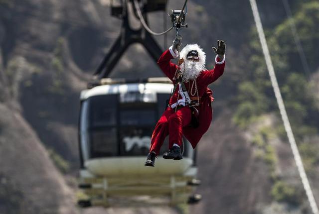 Foto: Un hombre vestido de Papa Noel desciende del cerro Pan de Azúcar como parte de las celebraciones por Navidad. EFE/ Antonio Lacerda