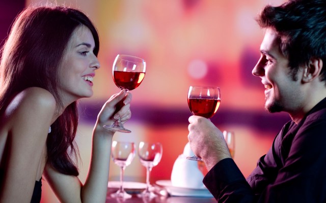 Young happy amorous couple celebrating with red wine at restaura