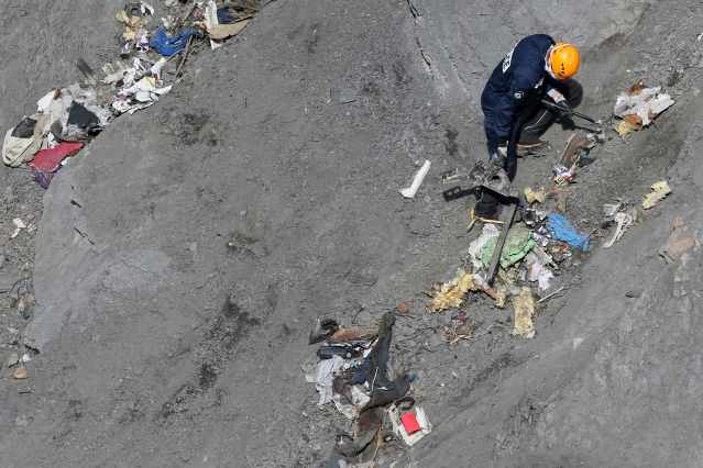 A French rescue worker inspects the debris from the Germanwings Airbus A320 at the site of the crash, near Seyne-les-Alpes, French Alps