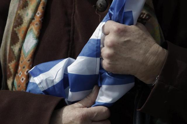 Una mujer sostiene una bandera griega durante uno de los actos celebrados con motivo del Día de la Independencia en Atenas (Grecia) hoy, martes 24 de marzo de 2015. EFE/Yannis Kolesidis