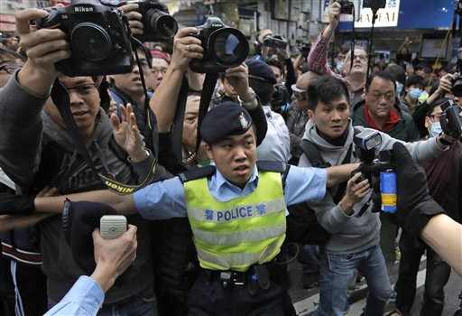 Un agente de policía intenta controlar los enfrentamientos entre activistas que protestan contra la proliferación de compradores de la China continental y residentes de Yuen Long en Hong Kong, el 1 de marzo de 2015. (Foto AP/Vincent Yu)