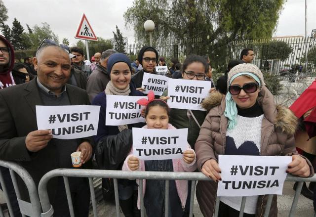  Un grupo de tuencinos muestra pancartas en las que se lee "Visita Túnez" junto al Museo Bardo tras su reapertura después del atentado de la pasada semana en Túnez (Túnez) hoy, martes 24 de marzo de 2015. Veinte turistas extranjeros y dos tunecinos perdieron la vida durante un atentado perpetrado por dos terroristas islamistas el 18 de marzo. El secretario general de la Organización Mundial del Turismo (OMT), Taleb Rifai, ha abogado hoy por no dejar de viajar a Túnez tras el atentado. Rifai ha apuntado que este tipo de sucesos pueden ocurrir en cualquier parte y ha avanzado que viajará a Túnez en los próximos días. EFE/Mohamed Messara