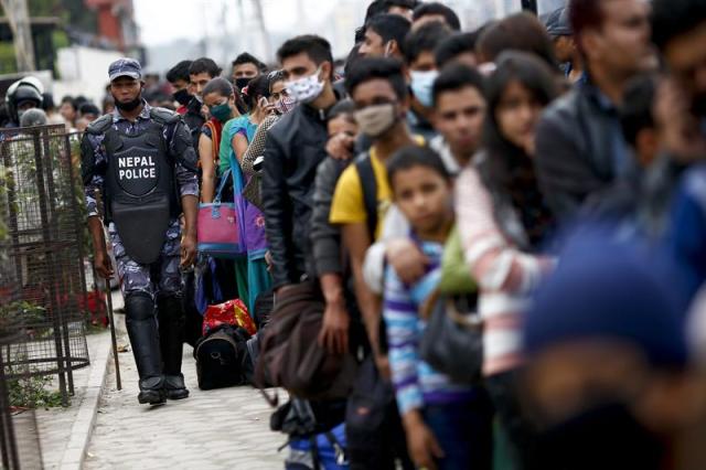 Un agente de la policía nepalí camina junto a una cola de gente que espera coger un autobús fletado por el gobierno para regresar a sus hogares a las afueras de Katmandú (Nepal) hoy, miércoles 29 de abril de 2015 tras el terremoto del pasado sábado. Los hospitales de la capital nepalí, Katmandú, se encuentran al límite de su capacidad mientras continúan llegando heridos desde otros distritos del país afectados por el terremoto que sacudió el sábado la nación del Himalaya. EFE/Diego Azubel