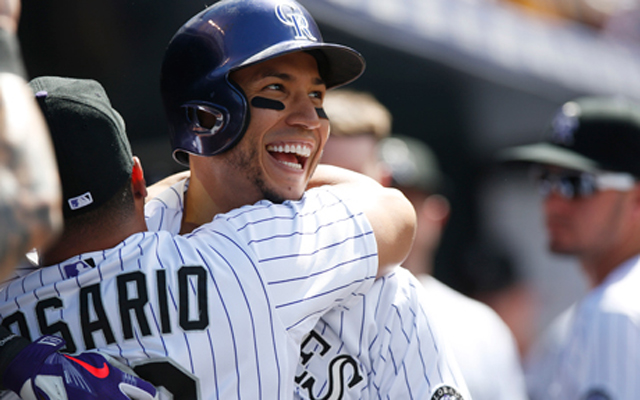 Colorado Rockies' Carlos Gonzalez, right, is hugged by teammate Wilin Rosario as Gonzalez returns to the dugout after hitting a two-run home run off Cincinnati Reds relief pitcher Dylan Axelrod in the third inning of a baseball game Sunday, July 26, 2015, in Denver. (AP Photo/David Zalubowski)