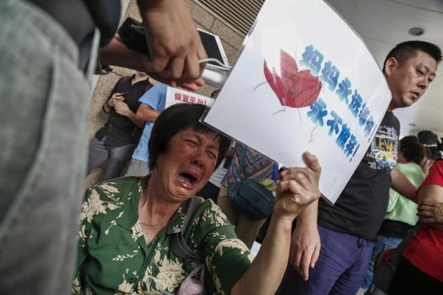  Una mujer llora a las puertas de las oficinas de Malaysia Airlines en Pekín (China) hoy 6 de agosto de 2015. China, de donde proceden 153 pasajeros del avión malasio desaparecido en marzo de 2014, pidió hoy a Malasia que continúe investigando las causas del accidente, después de que ese país confirmara que el "alerón" hallado en la isla de La Reunión pertenece al aparato Boeing 777 que cubría el vuelo MH370. EFE/Rolex Dela Pena