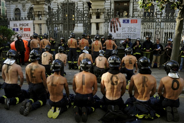 Los bomberos participan en una protesta frente al parlamento regional de Asturias exigiendo mejores salarios y mayores estándares de seguridad pública en Oviedo, norte de España, 19 de noviembre de 2015. Las letras pintadas sobre las espaldas de los hombres forman las palabras que decían: "El PSOE (Partido Socialista de España) le pone en peligro ". REUTERS / Eloy Alonso