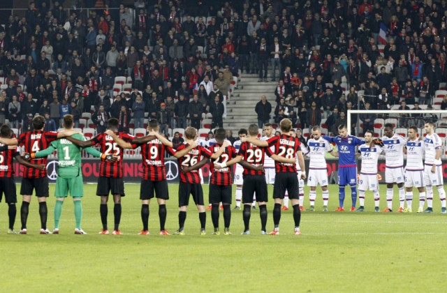 Jugadores del Niza, izquierda, y Lyon guardan un minuto de silencio previo a un partido de la liga francesa en Niza el viernes 20 de noviembre de 2015. (AP Foto/Lionel Cironneau)