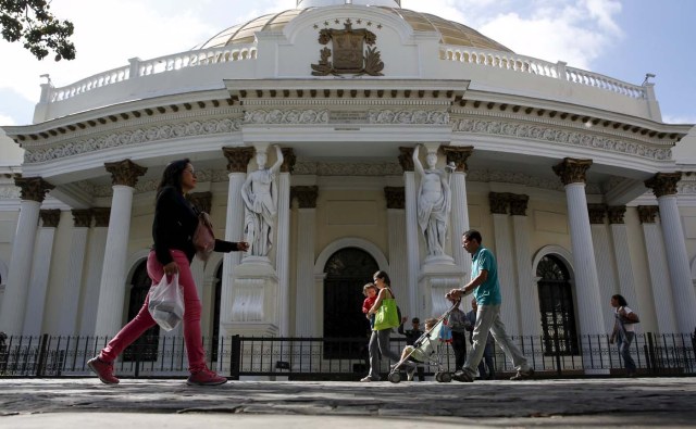 People walk past the National Assembly building during a session in Caracas December 23, 2015. REUTERS/Carlos Garcia Rawlins