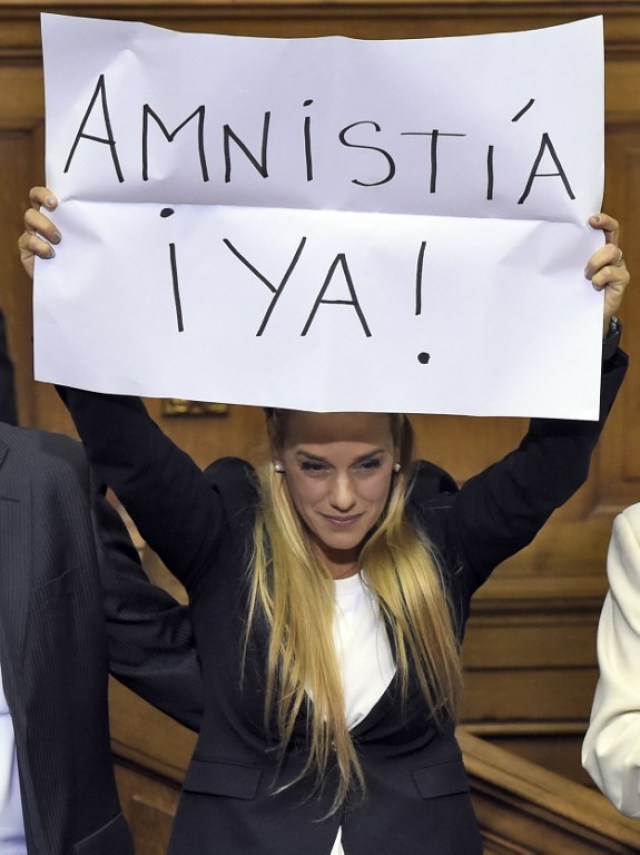 The wife of jailed Venezuelan opposition leader Leopoldo Lopez, Lilian Tintori shows a banner asking for an immediate amnesty for political prisoners at the Venezuelan parliament in Caracas, on January 5, 2016.  Venezuela's President Nicolas Maduro ordered the security forces to ensure the swearing-in of a new opposition-dominated legislature passes off peacefully Tuesday, after calls for rallies raised fears of unrest. AFP PHOTO/JUAN BARRETO / AFP / JUAN BARRETO