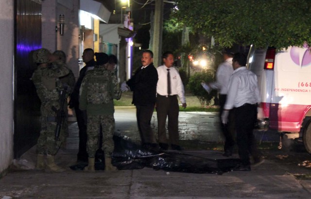 Forensic technicians and soldiers stand outside a safe house where five people were shot dead during an operation to recapture drug lord Joaquin "El Chapo" Guzman in Los Mochis, Mexico, January 8, 2016. REUTERS/Jesus Bustamente EDITORIAL USE ONLY. NO RESALES. NO ARCHIVE.