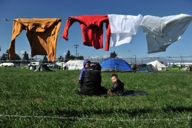 Los niños esperan con otros migrantes y refugiados a cruzar la frontera entre Grecia y Macedonia, cerca de la localidad de Idomeni, el norte de Grecia, el 25 de febrero de 2016. Con la llegada de inmigrantes y refugiados en Europa superando 110.000 en los dos primeros meses del año, los Estados Naciones advirtieron que las restricciones fronterizas impuestas por algunos estados podría causar caos. restricciones de Macedonia han visto el número de llegadas lentos a cientos al día, aunque miles más siguen a la tierra todos los días en las islas griegas. Alrededor de 3.000 personas estaban esperando en el paso fronterizo Idomeni entre Grecia y Macedonia el 24 de febrero, informó la policía local. SAKIS MITROLIDIS / AFP