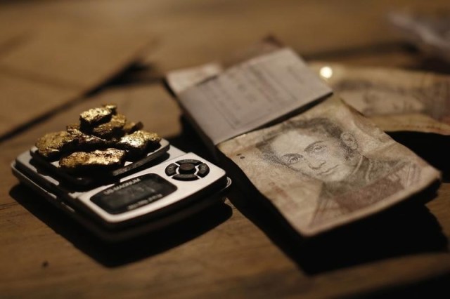 Extractos de oro en una pesa junto a billetes de bolívares venezolanos, en una villa indígena en Parkupik, en Bolívar, Venezuela.  (Foto REUTERS/Jorge Silva)