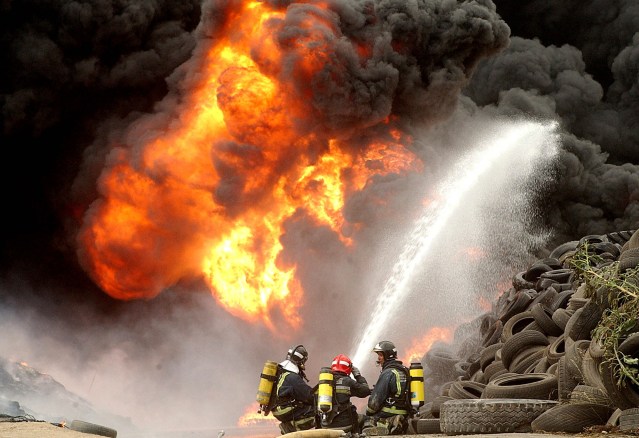 MUR02 Ceutí (Murcia), 31-07-05.- Efectivos de bomberos tratan de sofocar el incendio originado en el exterior de una nave industrial de neumáticos de la localidad murciana de Ceutí que comenzó a arder a primeras horas de esta tarde por causas que hasta el momento se desconocen. EFE/ISRAEL SANCHEZ