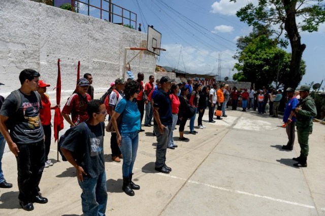 People receive instructions for military exercises to be conducted in the upcoming days at the low-income neighbourhood of Catia in Caracas on May 20, 2016. Venezuela was to launch Friday what it called its biggest-ever military exercises as unpopular President Nicolas Maduro sought to display his grip on power amid an economic meltdown and a push to vote him out of office. / AFP PHOTO / FEDERICO PARRA