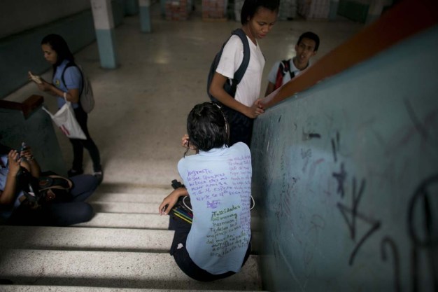 Fotografía del 31 de mayo de 2016 muestra un estudiante con una camisa de uniforme cubierta con mensajes escritos a mano por sus compañeros, un ritual de fin de cursos, en una escuela secundaria pública en Caracas, Venezuela. Una cuarta parte de los estudiantes venezolanos perdieron parte de las clases este año debido a hambre, según la organización sin fines de lucro Fundación Bengoa. (AP Foto/Ariana Cubillos)