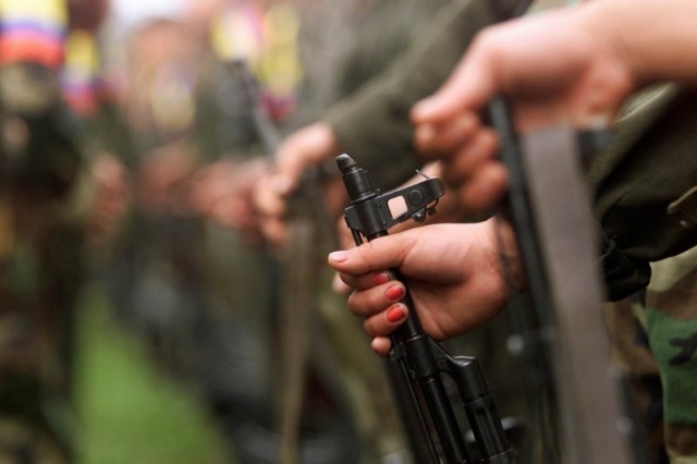 Una mujer colombiana sostiene su arma mientras participa de una parada militar de las FARC, en el campamento Villa Colombia, cerca de San Vicente del Caguán, Colombia. 29 de abril de 2000. El Gobierno de Colombia y la guerrilla izquierdista de las FARC firmarán el jueves un histórico acuerdo para decretar el cese al fuego bilateral y definitivo entre las partes, un pacto que marcará el fin de la confrontación armada más antigua del hemisferio. REUTERS/Jose Miguel Gomez/File Photo