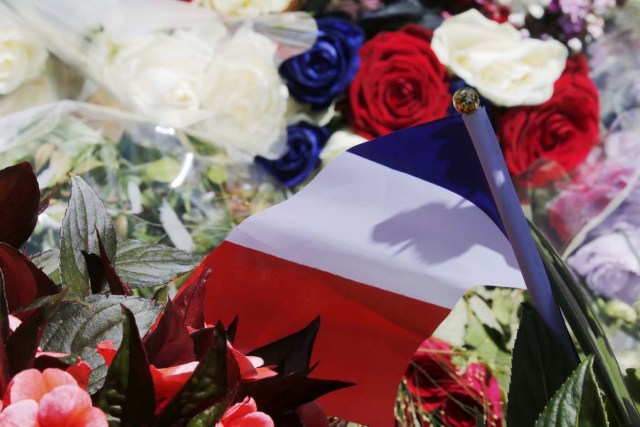 A bouquet of flowers and a French flag is seen as people pay tribute near the scene where a truck ran into a crowd at high speed killing scores and injuring more who were celebrating the Bastille Day national holiday, in Nice, France, July 15, 2016. REUTERS/Pascal Rossignol