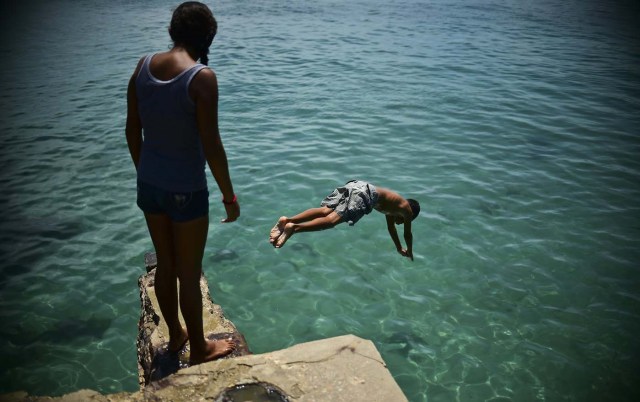 Youngsters dive in a beach of Pampatar, Margarita Island during the Non-Aligned Movement (NAM) summit, on September 15, 2016. / AFP PHOTO / RONALDO SCHEMIDT