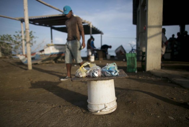 En esta imagen, tomada el 13 de septiembre de 2016, un vendedor callejero ofrece sardinas, que están en un cubo, en La Guardia, en la isla de Margarita, Venezuela. Los turistas extranjeros dejaron de llegar a Venezuela hace unos años mientras el país se convertía en uno de los más peligrosos del mundo, y el complejo sistema monetario actual dificulta el cambio de divisas. (AP Foto/Ariana Cubillos)