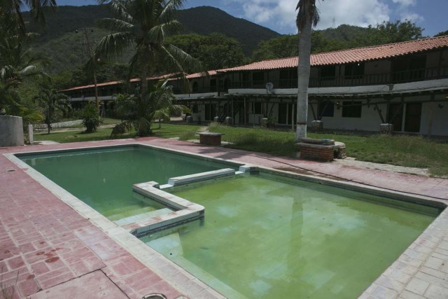 En esta imagen, tomada el 12 de septiembre de 2016, aguas turbias llenan unas piscina en el Hotel Balcones de Tacarigua, en la isla de Margarita, Venezuela. Los pocos clientes que siguen reservando habitaciones aquí tienen que traer su propio jabón, toallas e incluso papel sanitario, y la escasez de comida ha obligado al propietario del hotel a suspender el servicio de comidas. (AP Foto/Ariana Cubillos)