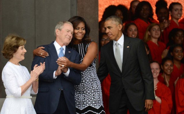 WASHINGTON, DC - SEPTEMBER 24: President Barack Obama watches first lady Michelle Obama embracing former president George Bush, accompanied by his wife, former first lady Laura Bush, while participating in the dedication of the National Museum of African American History and Culture September 24, 2016 in Washington, DC, before the museum opens to the public later that day. The museum is a Smithsonian Institution museum located on the National Mall featuring African American history and culture in the US. Astrid Riecken/Getty Images/AFP