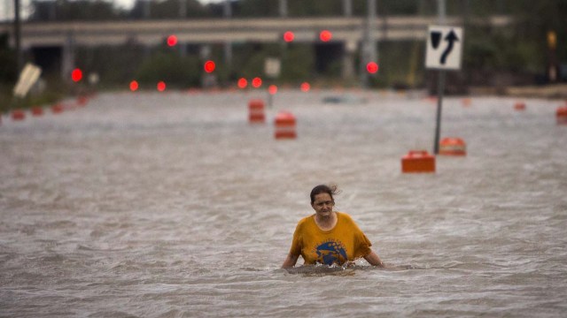 Una mujer que solo se identificó como Valerie camina por una calle inundada tras el paso del huracán Matthew luego de haber salido de un campamento para indigentes el sábado 8 de octubre de 2016, en Savannah, Georgia. (AP Foto/Stephen B. Morton)