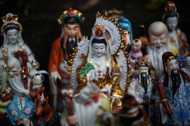 This picture taken on August 9, 2016 shows a display of unwanted statues of deities, gathered and repaired after their owners discarded them, on a rocky slope running down to the sea in Hong Kong. Religion and local customs permeate Hong Kong, where Buddhist and Taoist temples are common and incense offerings are regularly burned outside local businesses. Private homes often have a shrine to a local deity, with Christian churches and mosques also in the mix. But with space at a premium in a city were rents are sky high, informal collections of discarded gods often decorate roadsides and public spaces. / AFP PHOTO / Anthony WALLACE / To go with "HONG KONG-CULTURE-LIFESTYLE-RELIGION", FEATURE by Dennis Chong