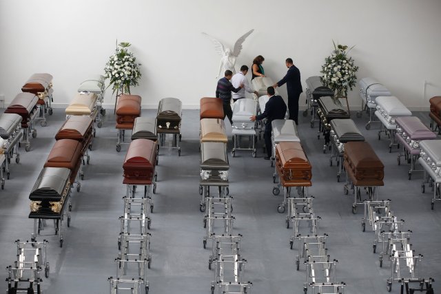 Funeral workers arrange coffins holding the remains of the victims who died in an accident of the plane that crashed into the Colombian jungle with Brazilian soccer team Chapecoense onboard, in Medellin, Colombia December 1, 2016. REUTERS/Jaime Saldarriaga