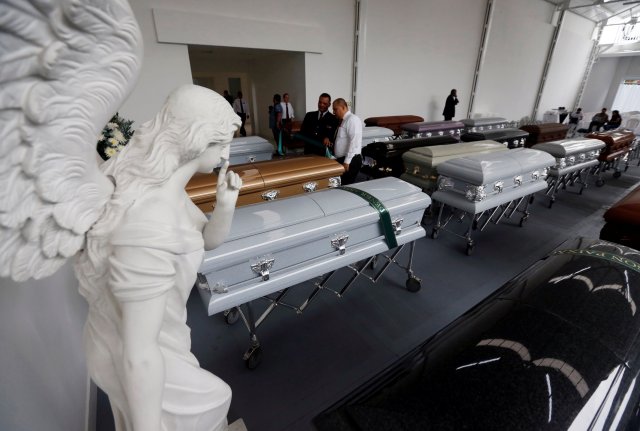 Funeral workers place ribbons with names on the coffins holding the remains of the victims who died in an accident of the plane that crashed into the Colombian jungle with Brazilian soccer team Chapecoense onboard, in Medellin, Colombia December 1, 2016. REUTERS/Jaime Saldarriaga