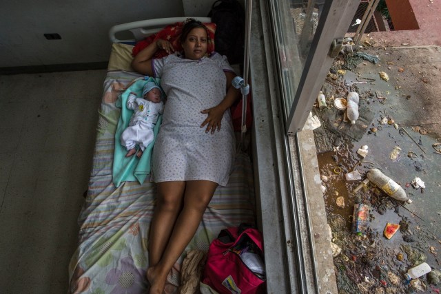 En esta foto del 5 de noviembre de 2016, Virginia Vargas descansa junto a su bebé de un año en la sala de maternidad en el hospital público de Cumaná, estado de Sucre, Venezuela. De acuerdo con el obstetra Javier Vegas, el hospital no tiene los suministros básicos, por lo que los doctores tienen que lavar y reusar materiales para suturar y muchas mujeres que dan a luz llegan a tener infecciones. (AP Foto/Rodrigo Abd)