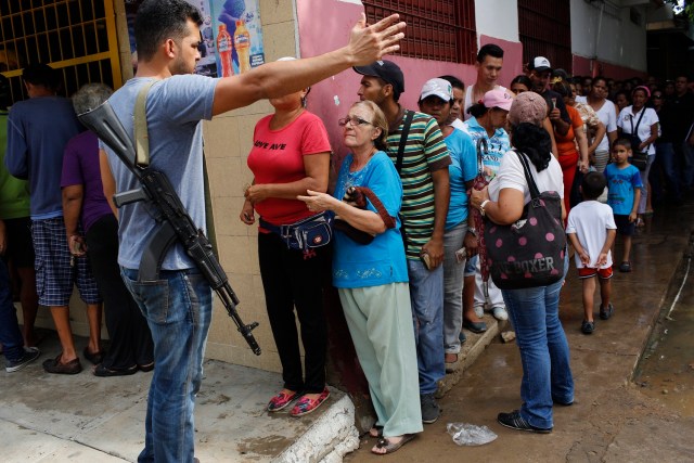 En esta foto del 4 de noviembre de 2016, un oficial del comando antisecuestro y contra la extorsión de la Guardia Nacional da instrucciones a la gente que se forma para comprar comida en una tienda en el centro de Cumaná, estado de Sucre, Venezuela. Los agentes de esa corporación resguardan los lugares a los que llegarán camiones con comida. (AP Foto/Rodrigo Abd)