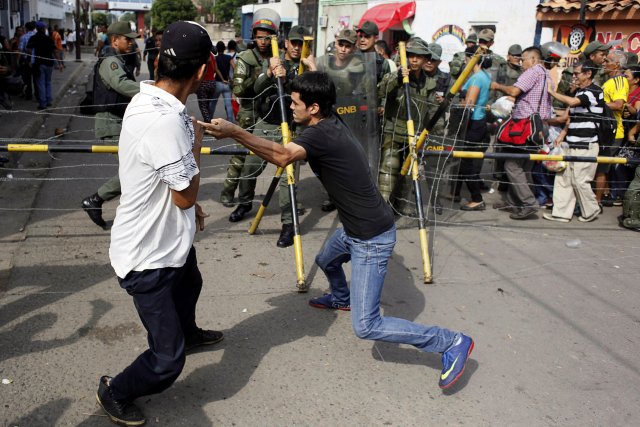 People clash with Venezuelan National Guards as they try to cross the border to Colombia over the Francisco de Paula Santander international bridge in Urena