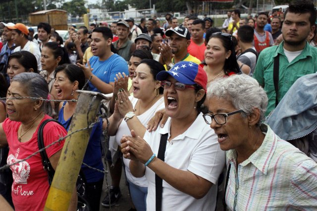 People shout slogans as they wait to try to cross the border to Colombia over the Francisco de Paula Santander international bridge in Urena