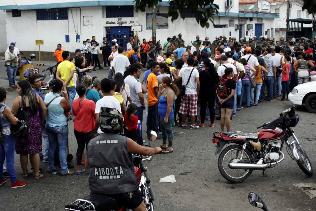 People make a line in front of Venezuelan National Guards as they wait to try to cross the border to Colombia over the Francisco de Paula Santander international bridge in Urena