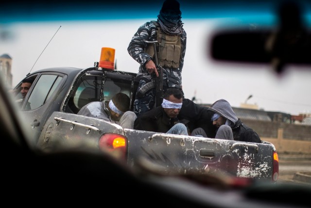 Christian militia fighters from the Nineveh Plain Protection Units (NPU) drive a pick-up truck in Qaraqosh (also known as Hamdaniya), transporting four men, allegedly members of the Islamic State (IS) group that were found inside a tunnel in Mosul, on December 20, 2016. / AFP PHOTO / JM Lopez