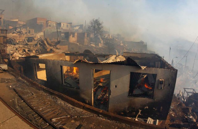 CH01. VALPARAISO (CHILE), 02/01/2017.- Vista de casas en medio de un incendio forestal en el sector de Playa Ancha en la ciudad de Valparaíso (Chile) hoy, 2 de enero de 2016, que afectó a viviendas y vecinos del sector. Un incendio forestal que estalló hoy en la parte alta del puerto chileno de Valparaíso llevó a las autoridades a declarar alerta roja en la ciudad y a disponer la evacuación preventiva de unas 25 viviendas próximas al foco de fuego, informaron fuentes oficiales. EFE/SEBASTIAN CISTERNAS