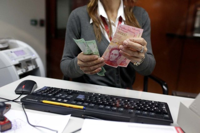 A bank teller counts bolivar banknotes at a Banco de Venezuela branch in Caracas, Venezuela January 16, 2017. REUTERS/Marco Bello