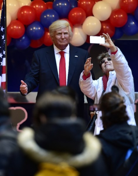 A woman takes a selfie with the wax statue of US President-elect Donald Trump during its presentation at the Wax Museum of Madrid on January 17, 2017. / AFP PHOTO / GERARD JULIEN