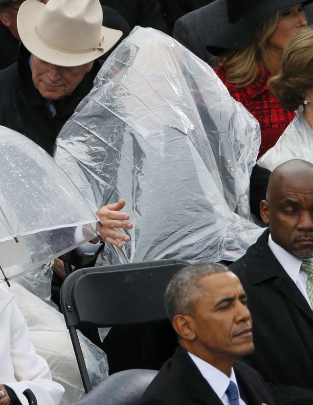 Former President George W. Bush keeps covered under the rain during the inauguration ceremonies swearing in Donald Trump as the 45th president of the United States on the West front of the U.S. Capitol in Washington, U.S., January 20, 2017. REUTERS/Rick Wilking