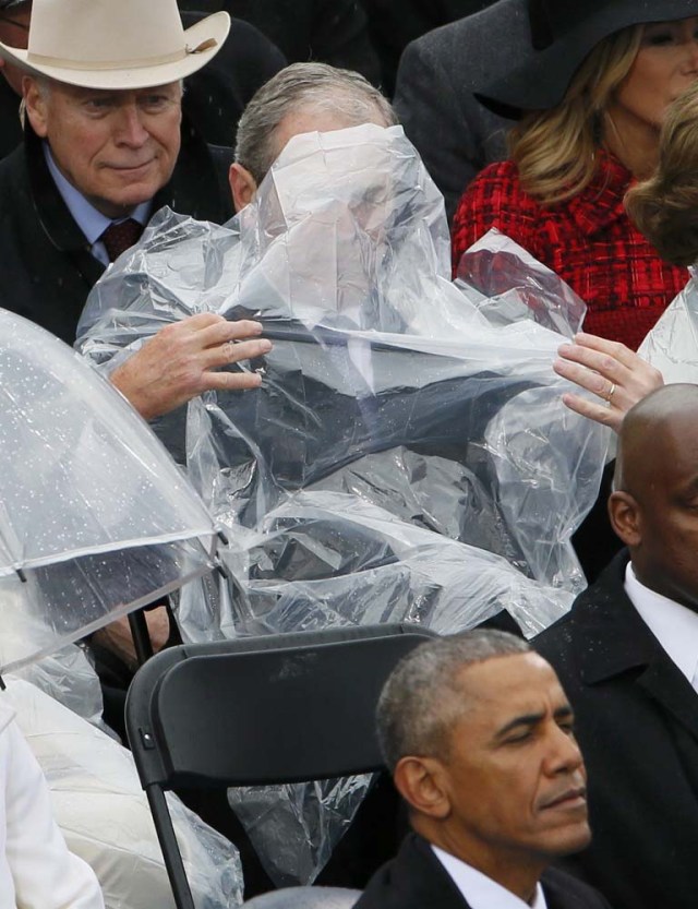 Former President George W. Bush takes off his cover under the rain during the inauguration ceremonies swearing in Donald Trump as the 45th president of the United States on the West front of the U.S. Capitol in Washington, U.S., January 20, 2017. REUTERS/Rick Wilking