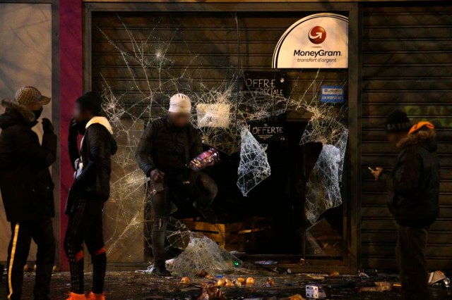 People gather by a vandalized Franprix supermarket during protest in Bobigny, a district of northeast Paris, to denounce police brutality after a black man was allegedly sodomised with a baton during an arrest while in their custody in Paris on February 11, 2017. A 22-year-old black youth worker named as Theo, a talented footballer with no criminal record, required surgery after his arrest on February 2, 2017 when he claims a police officer sodomized him with his baton. One officer has been charged with rape and three others with assault over the incident in the tough northeastern suburb of Aulnay-sous-Bois which has revived past controversies over alleged police brutality. / AFP PHOTO / GEOFFROY VAN DER HASSELT