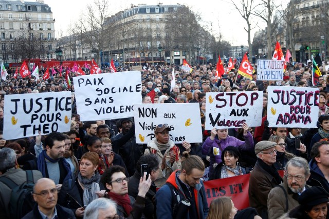 Demonstrators hold up placards to protest against police brutality after a young black man, 22-year-old youth worker named Theo, was severely injured during his arrest earlier this month in Bobigny, as people gather at a demonstration in Paris, France, February 18, 2017. REUTERS/Charles Platiau